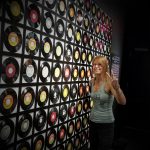 Radio DJ Michelle Parisi posing in front of records covering a wall
